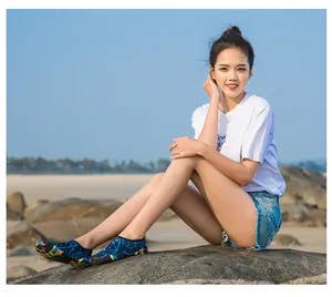 Jeune femme portant des chaussures d'eau à motifs bleus sur une plage de rochers