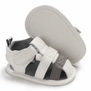 Detailed view of white soft-sole baby sandals with grey straps and velcro straps