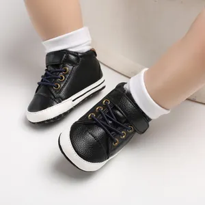 Close-up of black faux leather high-top baby walking shoes with soft white soles