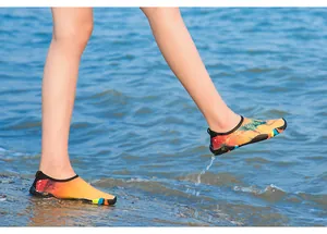 Chaussures aquatiques colorées portées sur la plage avec des vagues d'eau