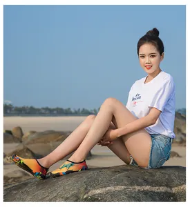 Femme asiatique sur rochers de plage portant des chaussures d'eau graffiti colorées