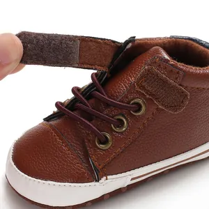 Detail showing the adjustable hook-and-loop closure on the brown leather baby shoe.