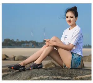 Femme asiatique sur un rocher de plage portant des chaussures d'eau pieds nus noires