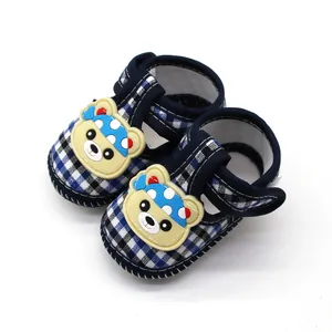Detailopname van blauwe geruite babysandalen met een schattige berenpatch en zachte antislipzool