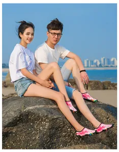 Couple asiatique portant des chaussures de plongée roses à motifs assis sur des rochers de plage