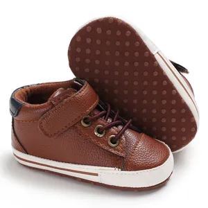 Detail of brown soft-sole leather baby pre-walker shoes with anti-slip dots on white background.