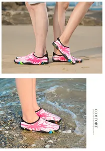 Couple portant des chaussures d'eau à motifs roses sur une plage de sable et un rivage rocheux
