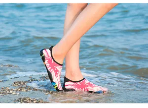Gros plan de chaussures d'eau à motifs roses portées dans l'eau de mer peu profonde