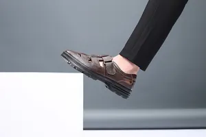 Vista lateral de sandalias de cuero marrón para hombre con diseño calado y velcro