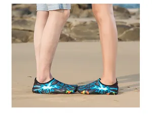 Gros plan d'un couple portant des chaussures d'eau à motif éclair bleu sur une plage de sable