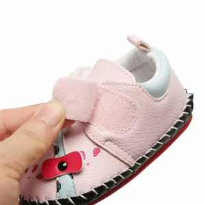 Détail en gros plan de la sangle velcro réglable sur une chaussure de marche pour bébé rose.