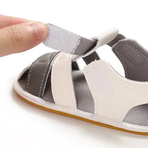 Detail showing the adjustable hook-and-loop strap on baby's white summer sandal