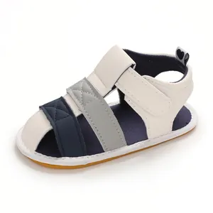 Side view of baby summer walking sandals with navy and grey straps and soft yellow sole