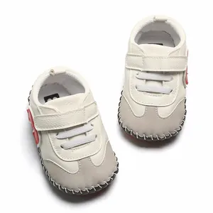 Détail de chaussures de marche pour bébé à semelle souple en cuir beige et suède gris.