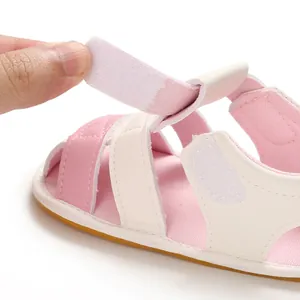 Detail showing the adjustable hook-and-loop strap on soft-soled pink baby sandals