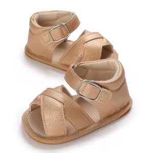 Close-up of golden metallic baby girl walking sandals with cross-straps and buckle