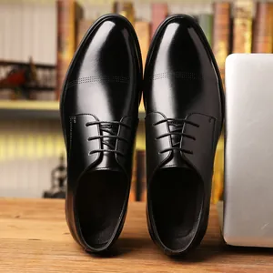 Classic black lace-up men's business casual leather shoes displayed on a wooden desk