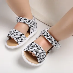 Close-up detail of black and white patterned breathable baby sandals with soft soles.