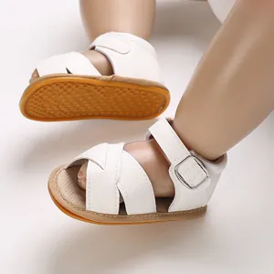 Close-up of white soft faux leather baby girl walker sandals with buckle strap and rubber sole