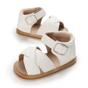 Close-up of white cross-strap baby walker sandals with soft tan rubber soles