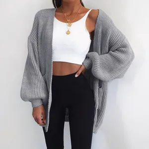 Vista dettagliata di un cardigan oversize grigio a maglia grossa con un crop top bianco