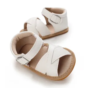 Detailed view of white soft sole pre-walker baby sandals featuring cross straps and buckle