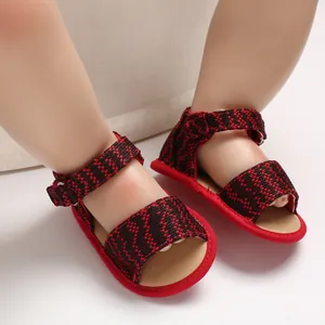 Close-up of red and black patterned baby walking sandals with soft soles and velcro strap