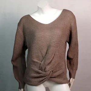 Detalle del suéter de punto con cuello en V que muestra el nudo frontal trenzado