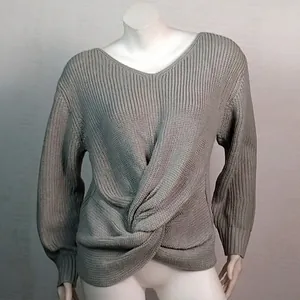 Detalle de jersey de punto gris con cuello en V y un moderno diseño de nudo frontal.