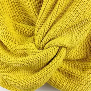Primer plano del elegante detalle del nudo trenzado y la textura suave de un suéter amarillo