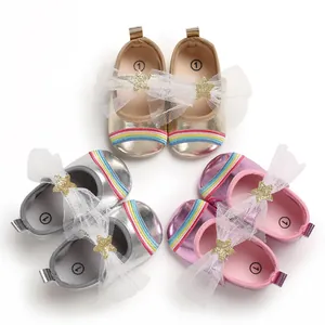 Detailed view of baby girl walking shoes in gold, silver, and pink with rainbow accents.
