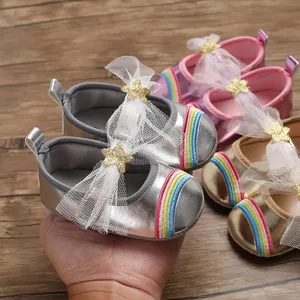 Detail view of soft-sole baby girl walker shoes with rainbow stripes and star bows.