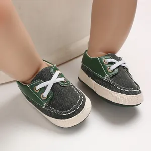 Detailopname van donkergroene denim babyloopschoenen met witte zachte zolen en veters.