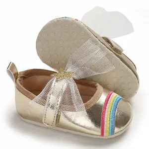 Close-up of baby girl shoes with gold metallic finish, tulle bow and rainbow embroidery