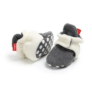Detailed view of soft grey fleece baby winter booties with white plush trim and polka dot soles