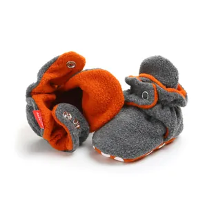 Close-up of winter baby fleece sock shoes featuring warm orange lining and snap buttons