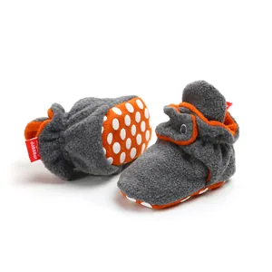 Close-up of grey and orange baby fleece booties with non-slip polka dot soles