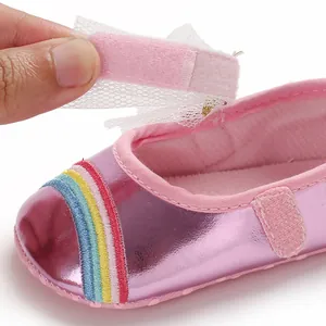 Close-up of pink baby girl walking shoe showing velcro strap and rainbow embroidery.