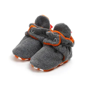 Detailed view of grey fleece baby booties with orange trim and soft non-slip soles