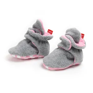 Close-up of grey and pink fleece baby booties with white non-slip dotted soft sole.