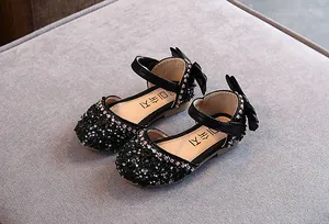 Detailopname van zwarte prinsessenschoenen voor meisjes met glinsterende strass en strikken