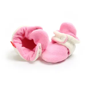 Close-up of pink fleece baby booties with soft sole and snap closure for winter