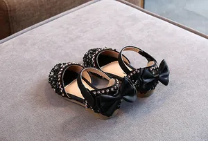 Detailopname van zwarte Mary Jane schoenen voor meisjes met strass en een grote zijden strik
