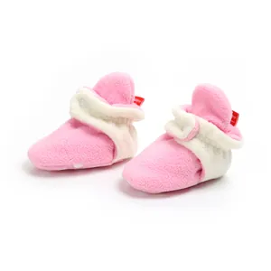 Close-up view of soft pink fleece winter baby booties with white cuffs and non-slip sole dots