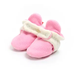 Detailed close-up of pink fleece baby booties featuring soft white lining and secure button