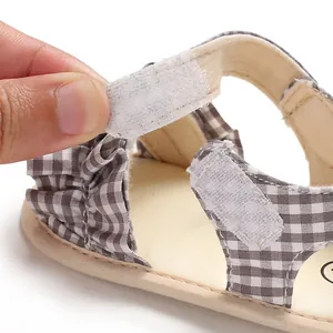 Dettaglio della chiusura in velcro regolabile sui sandali a quadretti per neonati