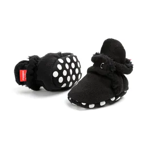 Close-up of black fleece baby booties featuring anti-slip polka dot soles and soft lining