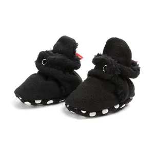 Macro view of black plush baby booties with soft soles and white spot patterns on the side.