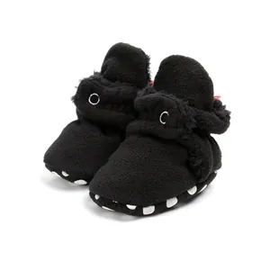 Macro view of fuzzy black baby winter walking shoes with non-slip polka dot soles