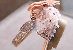 Detail van prinsessandalen voor meisjes met roze strassteentjes en stoffen bloem.